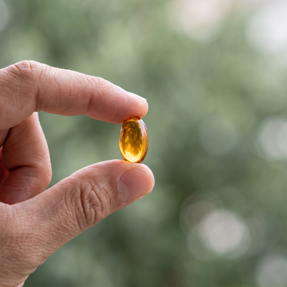 Hand holding a Vitasy Oil of Oregano softgel