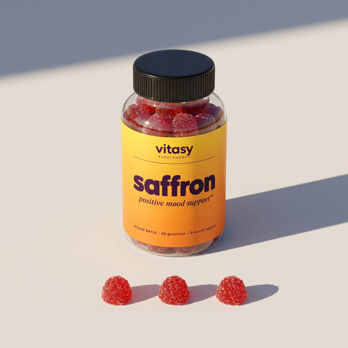 Vitasy Saffron Gummies bottle with three mixed berry gummies on a light background