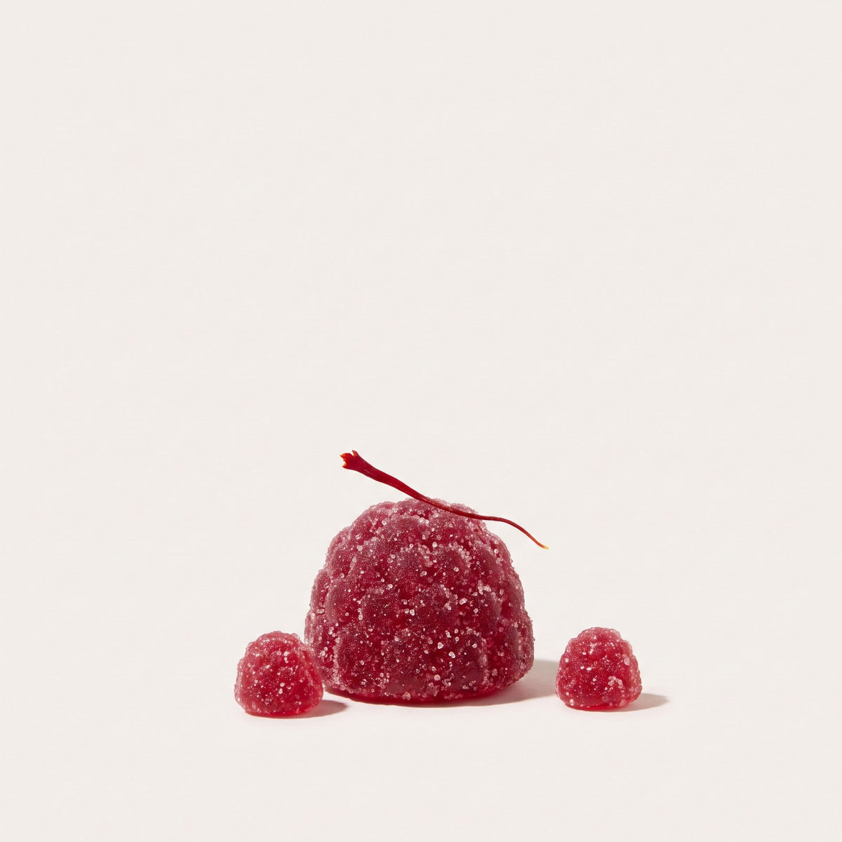 A single red mixed berry gummy topped with a saffron thread
