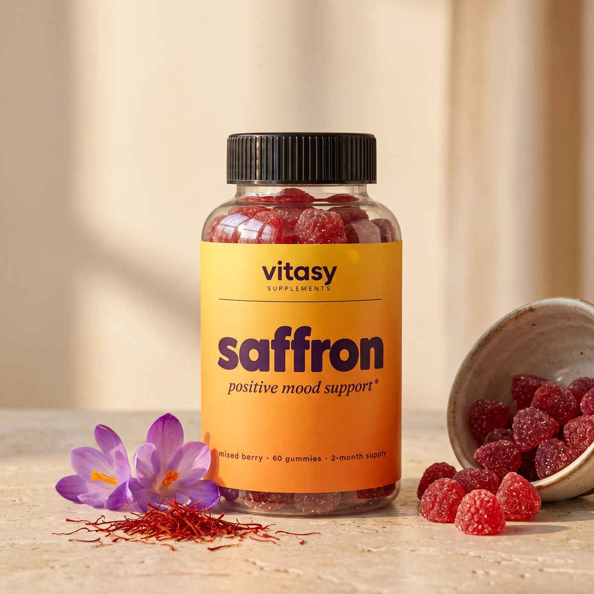 Vitasy Saffron Gummies bottle with saffron threads, crocus flowers and mixed berry gummies on a warm table