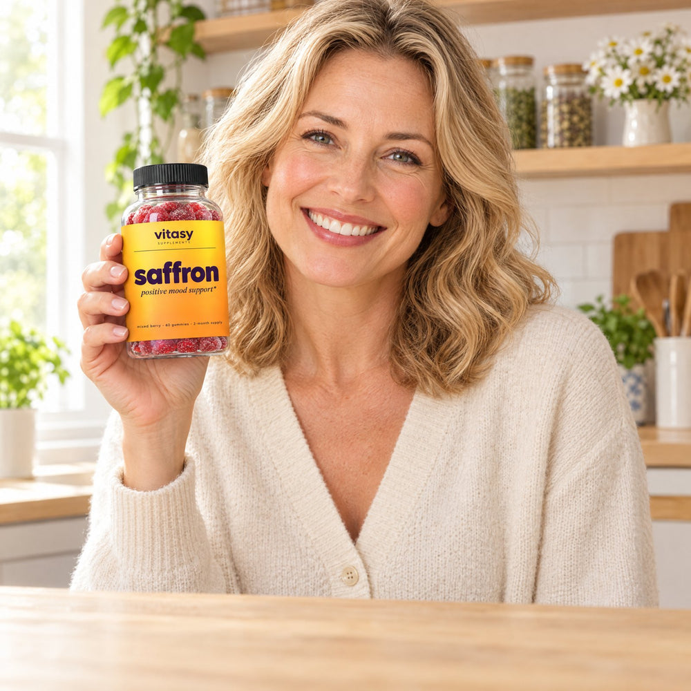 Smiling mother in her kitchen holding a bottle of Vitasy Saffron Gummies