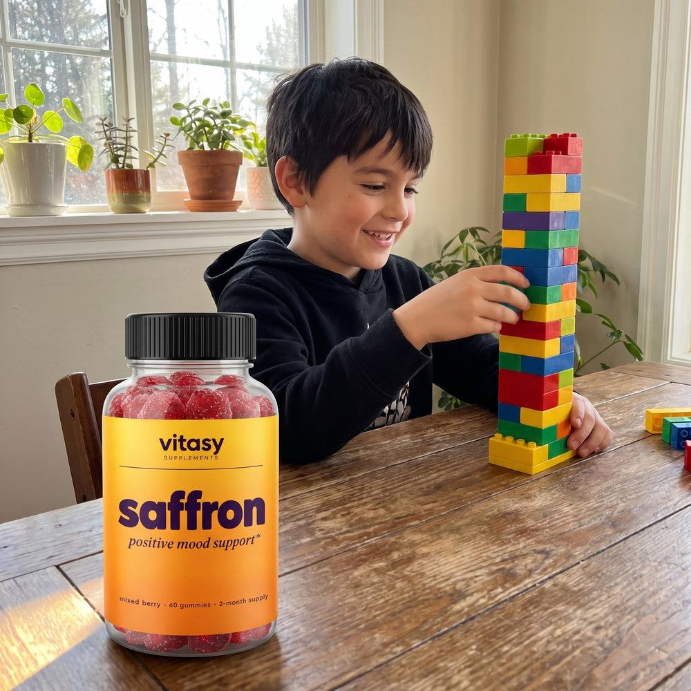 Boy building with toy blocks at the dining table, a bottle of Vitasy Saffron Gummies beside him
