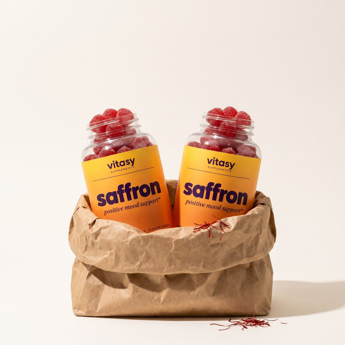 Two open bottles of Vitasy Saffron Gummies in a paper bag with saffron threads