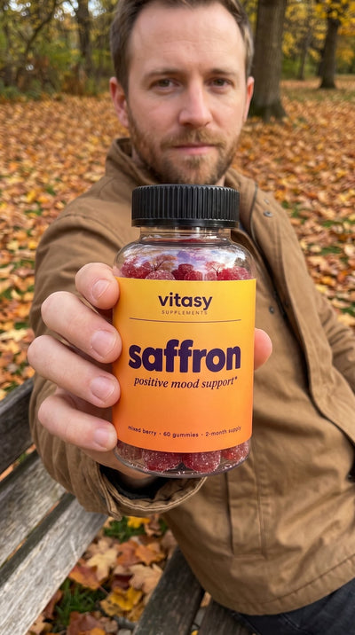 Man on a park bench holding Vitasy Saffron Gummies