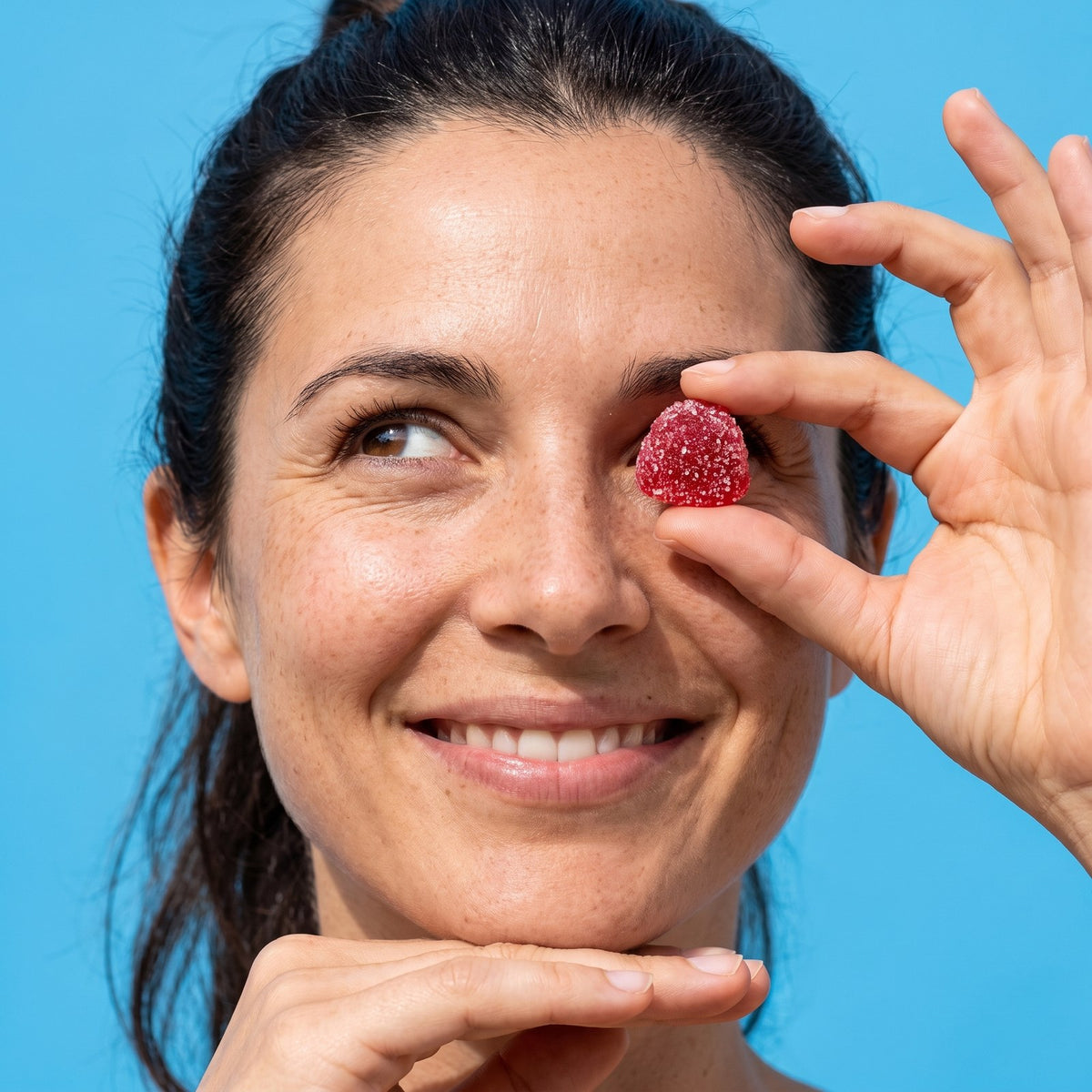 Smiling woman holding a mixed berry saffron gummy