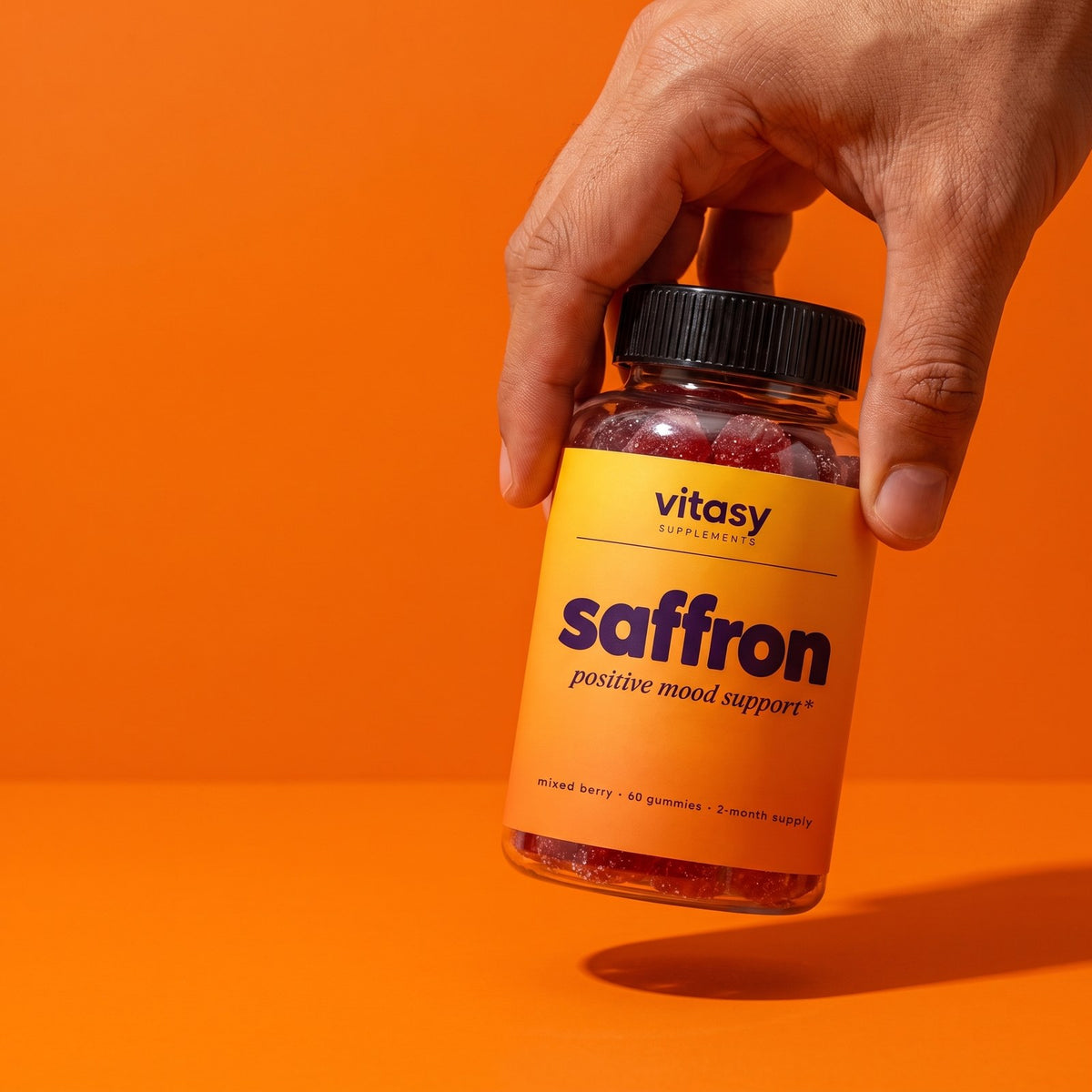 Hand holding Vitasy Saffron Gummies, mixed berry, 60 gummies
