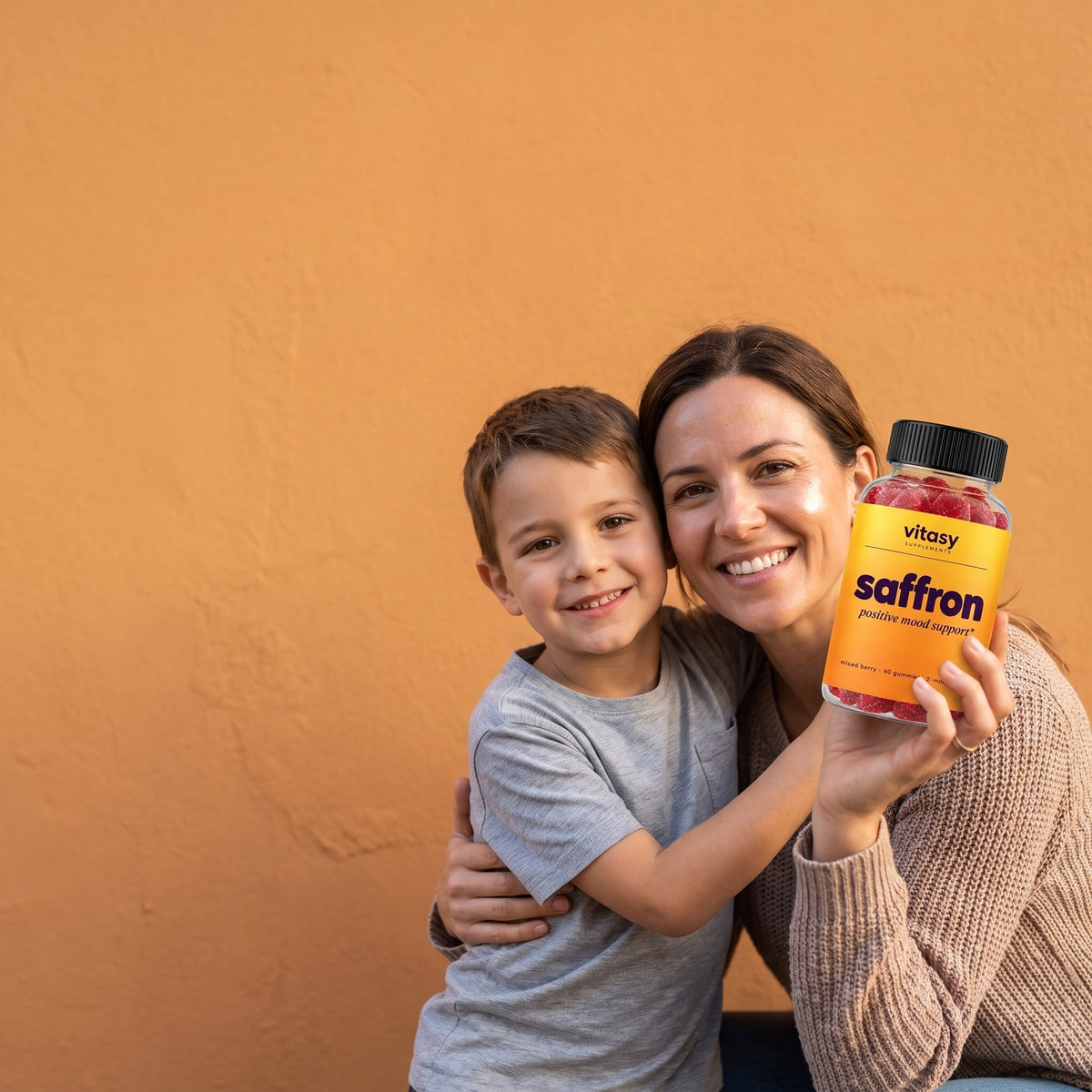 Mom and son smiling, mom holding a bottle of Vitasy Saffron Gummies