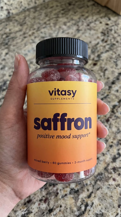 Close-up of a parent's hand holding the Vitasy Saffron Gummies jar