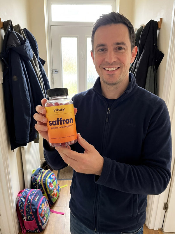 Dad holding a bottle of Vitasy Saffron Gummies in the hallway