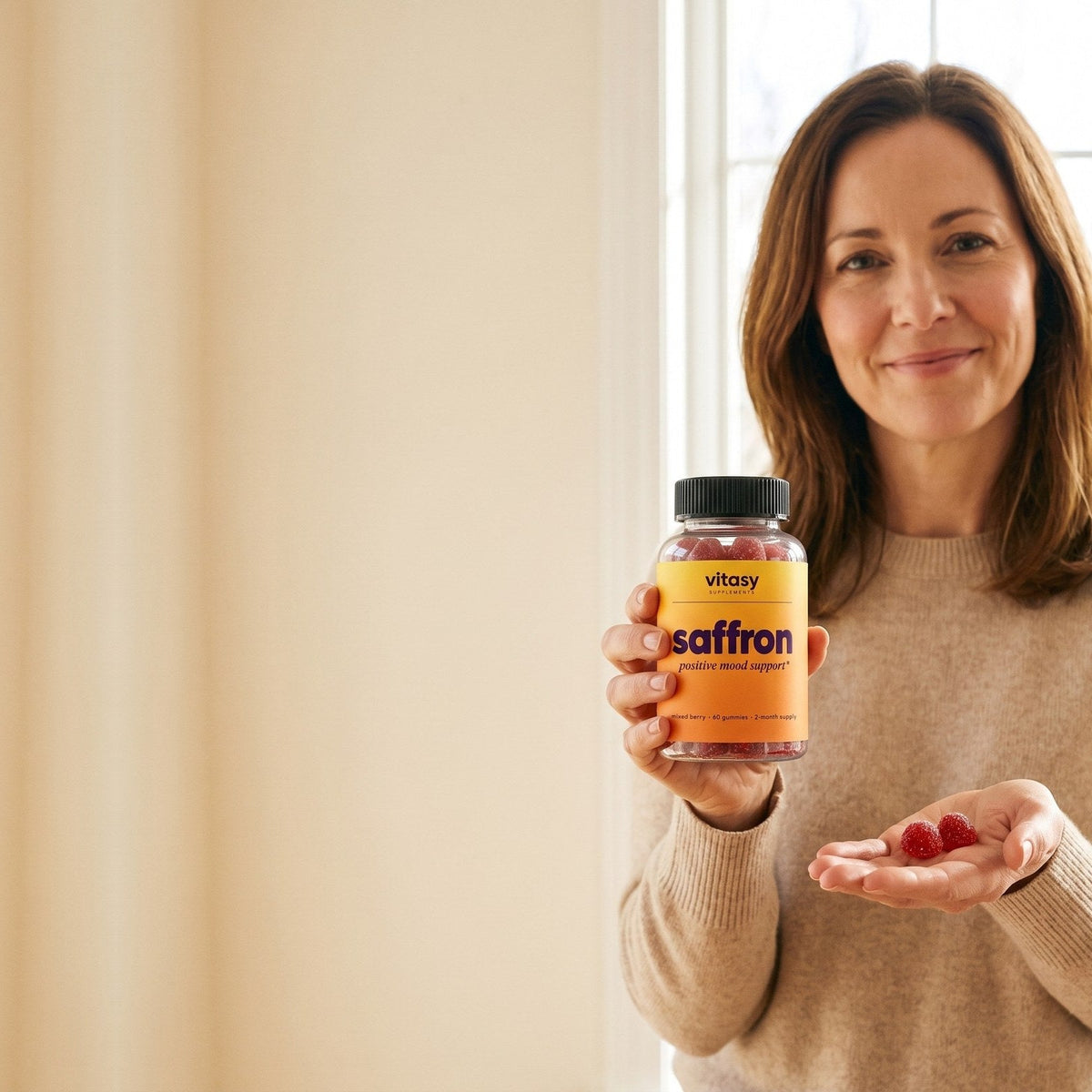 Parent holding Vitasy Saffron Gummies with two gummies in her hand