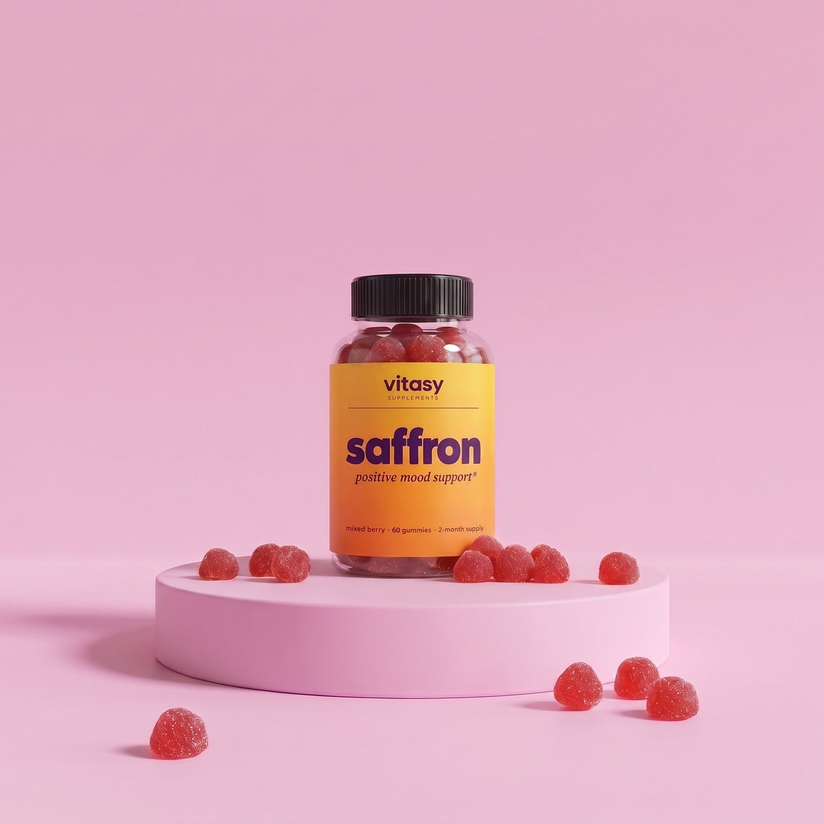 Vitasy Saffron Gummies jar on a pink podium with raspberry-shaped gummies