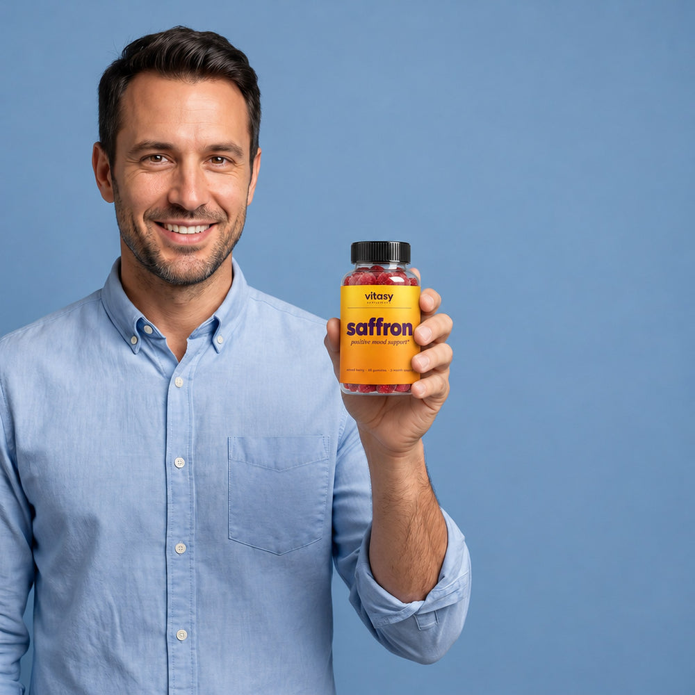 Smiling dad holding a bottle of Vitasy Saffron Gummies next to the Supplement Facts panel