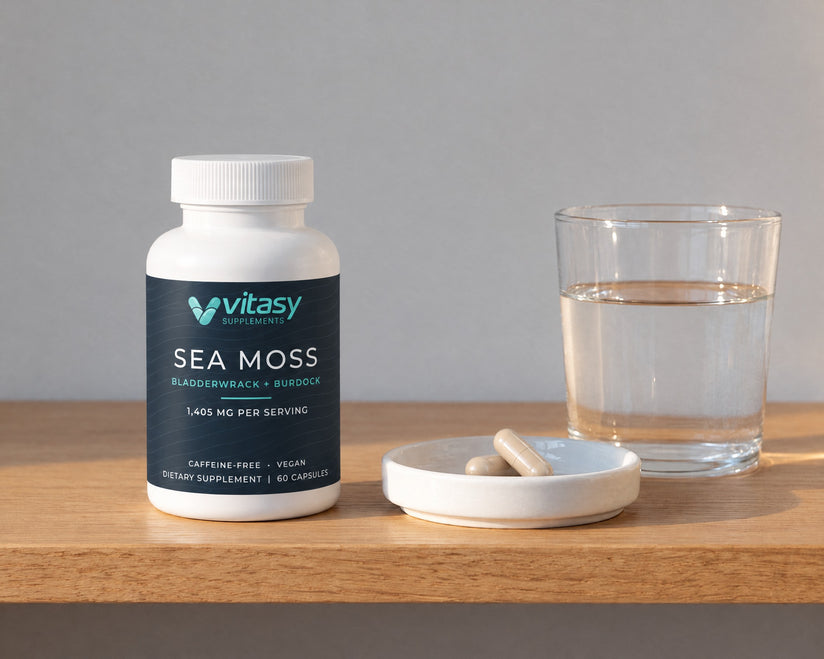 Two capsules on a small dish next to the Vitasy bottle and a glass of water